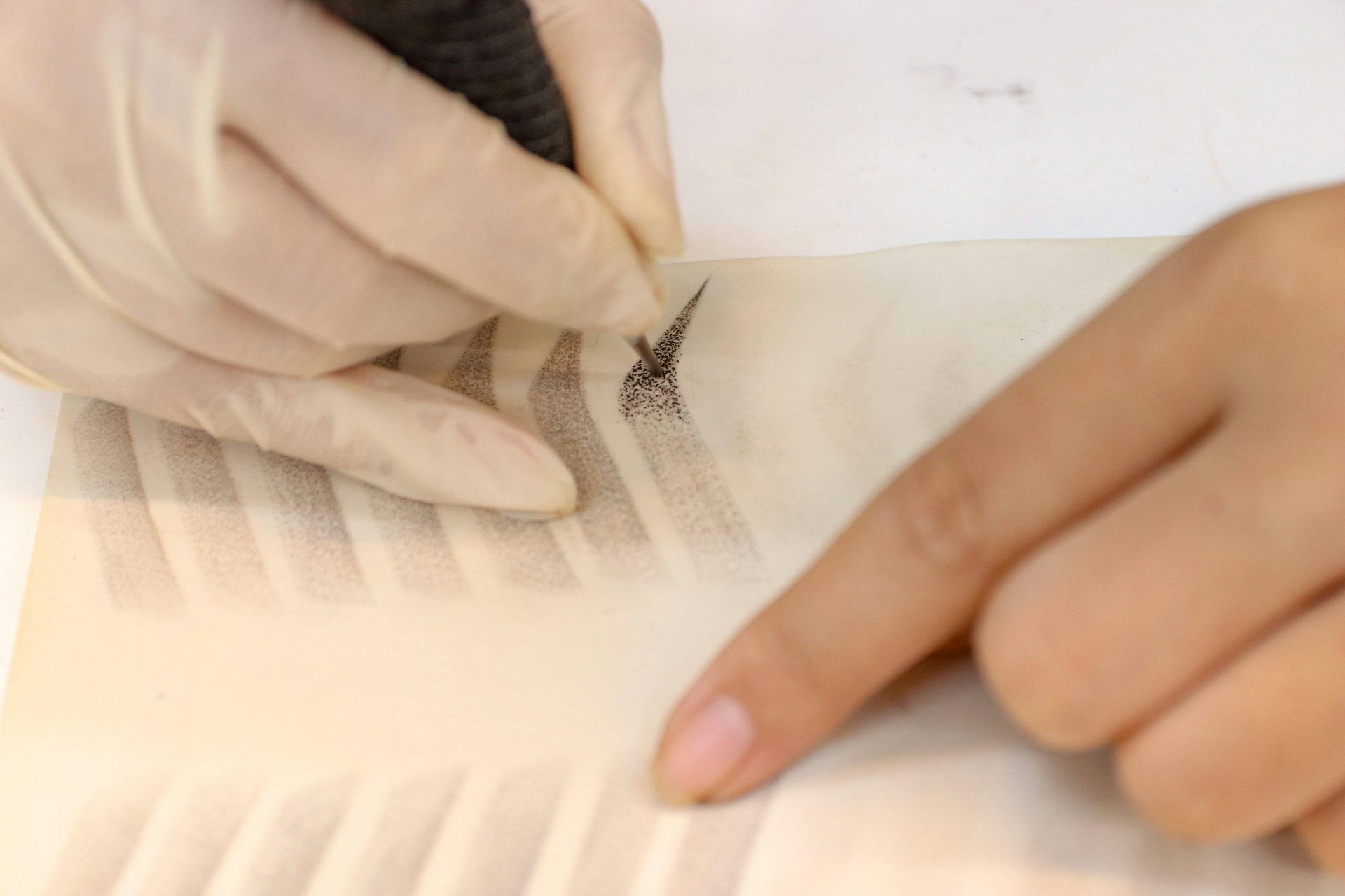 A person with a glove on writing on a piece of paper